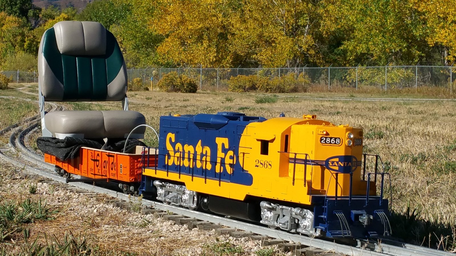 Yellow and blue Santa Fe miniature locomotive pulling a riding car at Rocky Mountain Rails